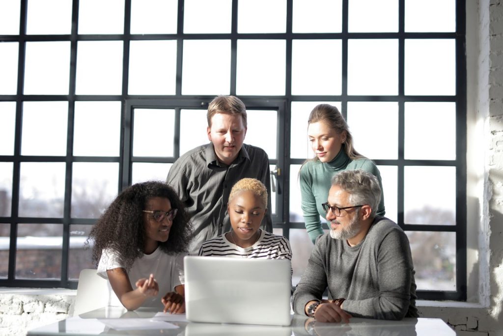 7 Best Mobile App Makers in 2022 To Make Your Own Mobile App - a group of people crowded around a laptop